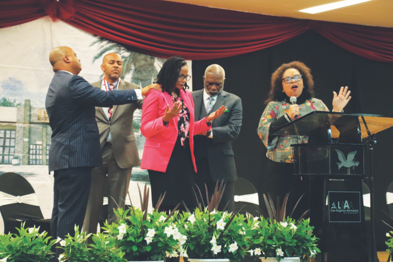 Benita R. Knight ora por la directora de LAAA, Carol Todd, mientras el orador Carlton P. Byrd, LAAA Alumni Association President de LAAA, Harold Burnett, y el vicepresidente de la Pacific Union Conference for Black Ministries, Virgil Childs, le imponen sus manos.