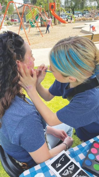 A volunteer finishes a face painting.