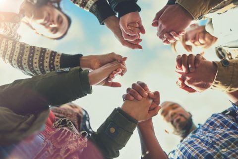 Shot of a group of friends putting their hands together in prayer