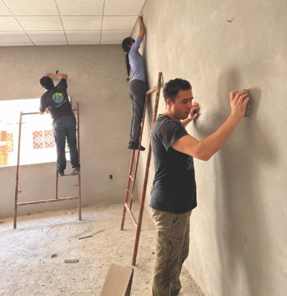 The team sands and washes the walls with materials they have on hand: bricks for sanding and cut-up jeans for washing.