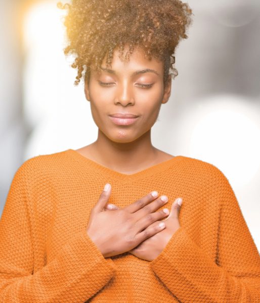 Beautiful young african american woman over isolated background smiling with hands on chest with closed eyes and grateful gesture on face. Health concept.