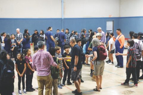 El personal y los estudiantes participan en el ejercicio de edificación de la comunidad «apretón de manos» durante el primer día de clases.