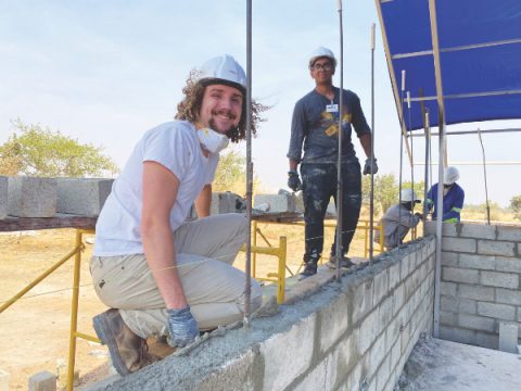 Volunteers offer smiles amid the physically demanding job of laying block walls. 