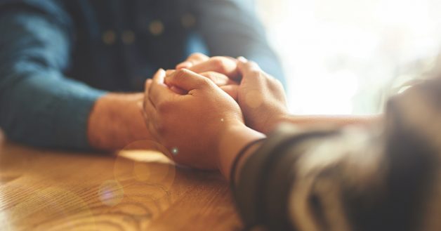Cropped shot of two people holding hands in comfort