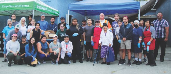 <p>Volunteers gather for a photo a few minutes before the gates open and distribution begins. The first shift of volunteers prepares the food on Friday, the second group packs the boxes on Saturday mornings, and this third group handles the distribution.</p><p>Los voluntarios se reúnen para tomarse una foto unos minutos antes de que se abran las puertas y comience la distribución. El primer turno de voluntarios prepara la comida el viernes, el segundo grupo empaca las cajas los sábados por la mañana y este tercer grupo se encarga de la distribución.</p>