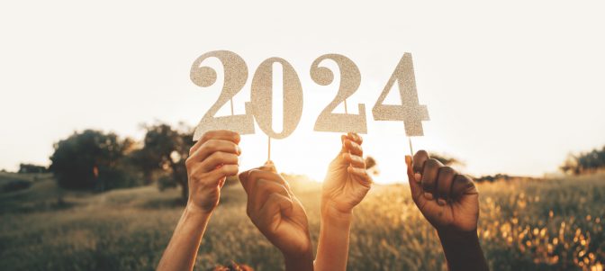 Group of friends holding 2024 paper numbers, to a year of peace success and achievements.