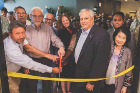 La congregación y los líderes se reúnen para cortar la cinta de las instalaciones renovadas.