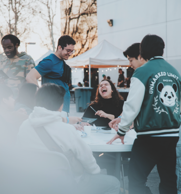 <p>Attendees laugh and mingle outside. </p><p>Los asistentes ríen y se mezclan afuera. 
</p>