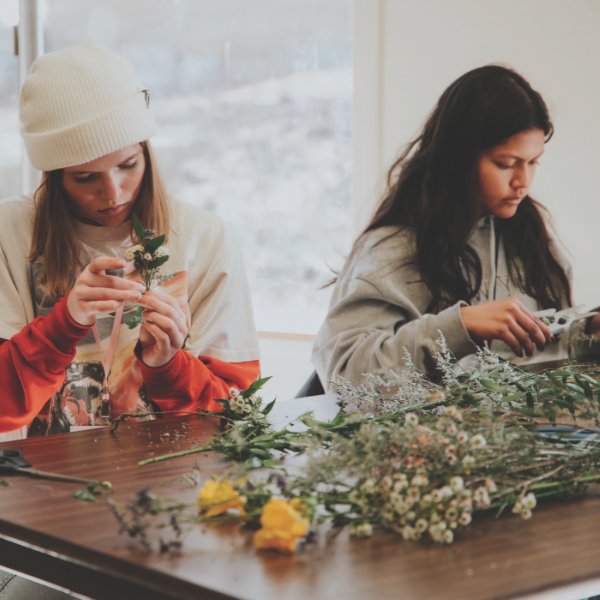 Two girls craft flower crowns together.