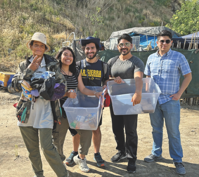 <p>A resident of a Riverside area encampment receives food and water from La Sierra students, left to right, Silvana Albornoz, Christian Figueroa, Armando Hernandez, and Ethan Miranda.</p><p>Un indigente del área de Riverside recibe comida y agua de los estudiantes de La Sierra, de izquierda a derecha, Silvana Albornoz, Christian Figueroa, Armando Hernández y Ethan Miranda</p>