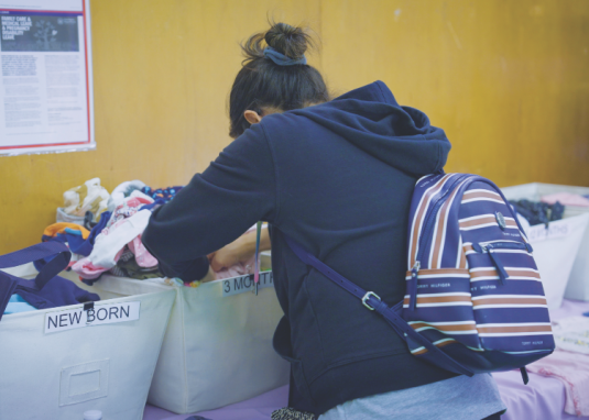 <p>A visitor looks through baby clothing categorized by size.</p><p>Una visitante revisa la ropa de bebé clasificada por talla</p>
