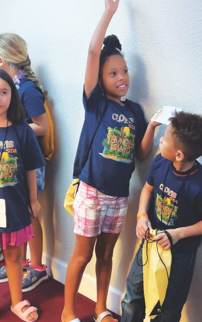 Una niña en Clovis levanta la mano queriendo ser elegida para compartir el punto de la Biblia.
