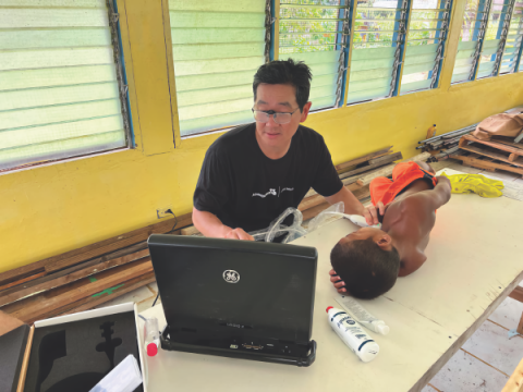 Dr. Peter Kim uses a portable cardiac ultrasound machine to screen a young patient in Chuuk.