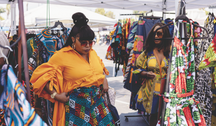 Los asistentes compran en un puesto que vende ropa africana.