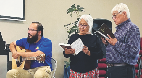 Gregory Holliday (right) along with his wife, Ella (center), and Pastor Gabriel Silva (left) lead the attendees in singing.