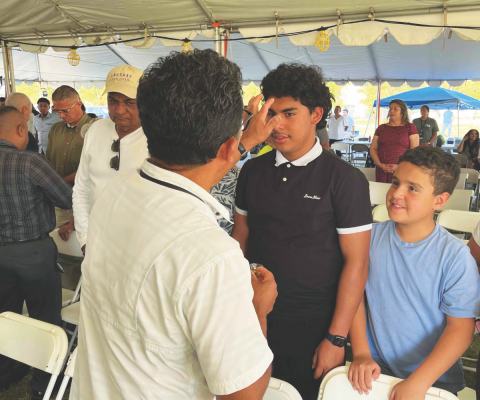“The priesthood of all believers” was the message of the anointing service from the pastors to the elders and the members. In this picture, an elder anoints a young man while another awaits his turn with a smile.
