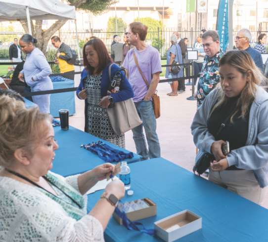 Delegates line up at designated registration tables in the courtyard to receive their badges.