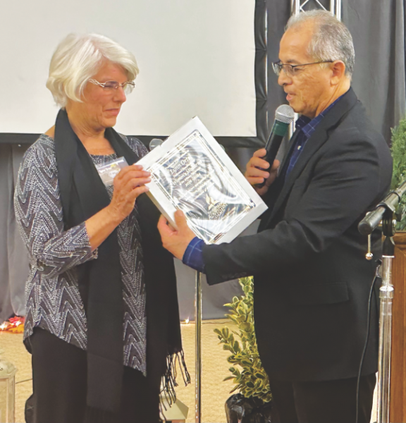 Arizona Conference Executive Secretary Ray Navarro hands Lynn Ortel a plaque to show appreciation for her years of service to the Women’s Ministries Department.