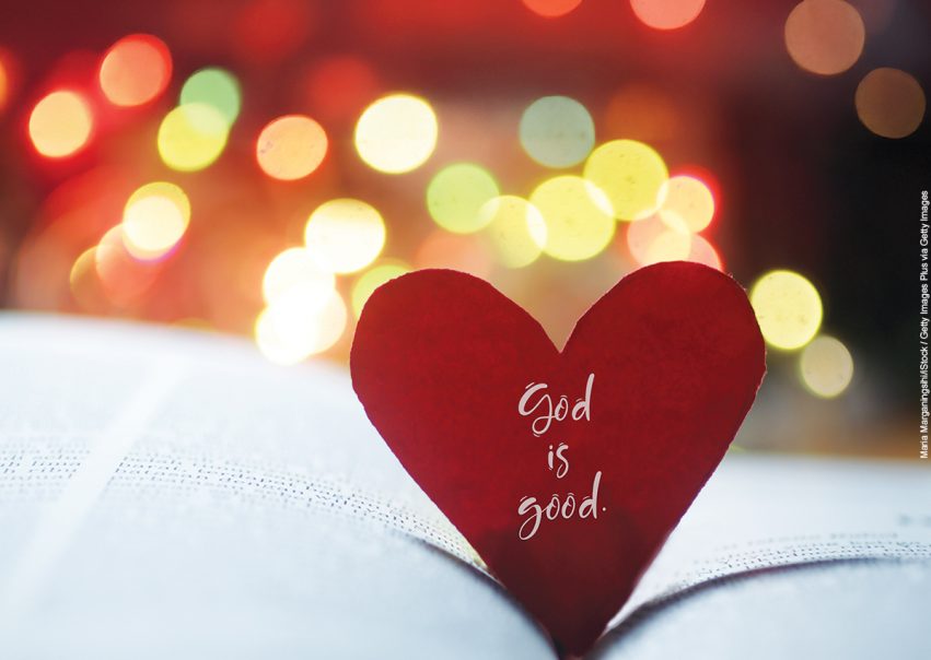 Spiritual inspirational quote - God is love. With hand holding red valentines day card with heart shaped paper on an open page of bible book and colorful bokeh background.