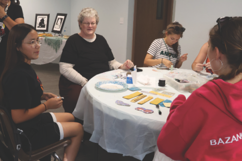 Left to right, Tresa and Ms. Donne chat with the girls while beading.