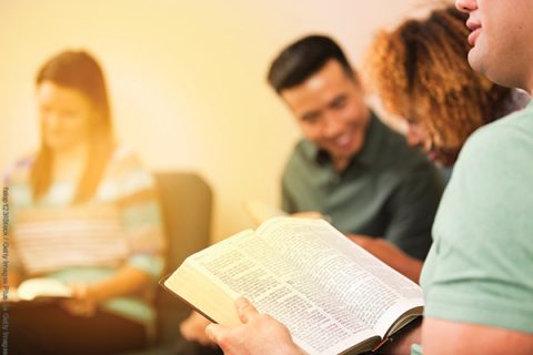 Multi-ethnic, mixed age group of people involved in Christian bible study meeting at local church.