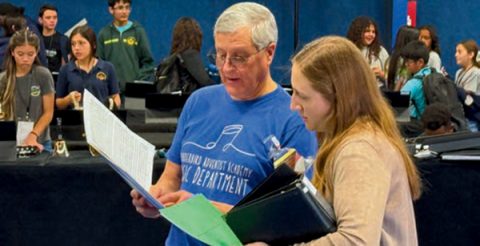 Band clinician Dean Kravig (left) reviews sheet music with choir clinician Lindsay Eldevik (right) during the rehearsal on Friday afternoon.