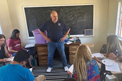 Chris Juhl (center) leads a standards-based learning planning session involving many of Arizona Conference's small school educators in Camp Yavapine's Little Red School House during last summer's Camp Meeting.