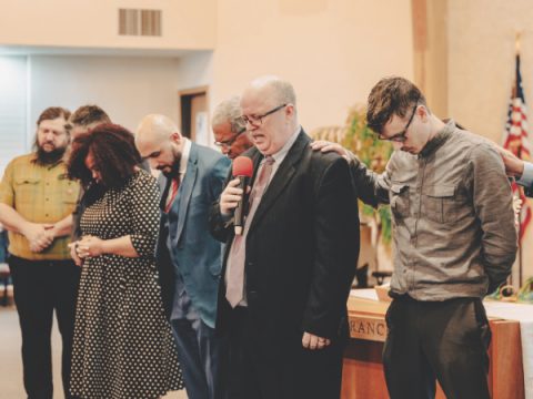 Elder Kent Sharpe, alongside pastors and elders from the conference and the Utah area, leads a prayer to empower the members for ministry.