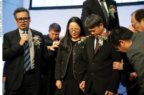 SCC Executive Secretary Danny Chan prays the ordination prayer as ordained ministers in attendance lay hands on Zhang and his wife