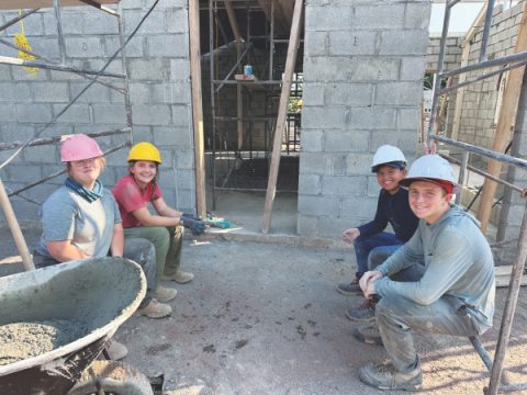 Los voluntarios toman un breve descanso frente a los muros que ayudaron a construir.