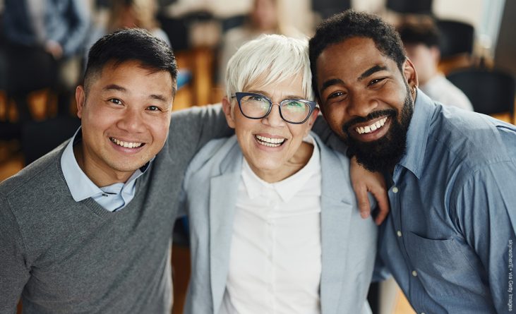 Portrait of happy diverse entrepreneurs standing embraced on a seminar in board room and looking at camera.