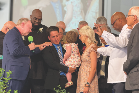 Arizona Conference administrators and pastors participate in a prayer of blessing on Zachary Surovec and his family during the ordination service.