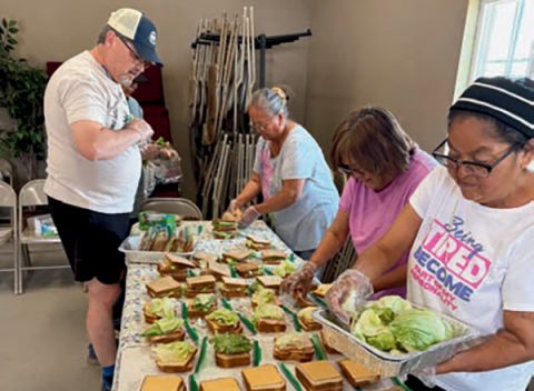 Volunteers build sandwiches in assembly line fashion as they prepare lunches for the firefighters.