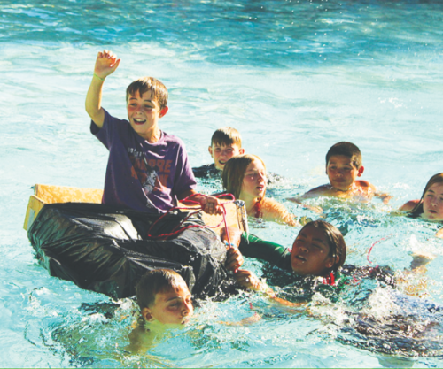 Los campistas participan en las «Olimpiadas» acuáticas en la piscina del campamento.