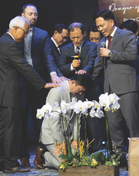 Lee is blessed by several pastors.