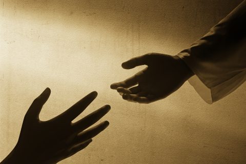 Jesus Christ giving a helping hand to human with wall background