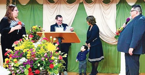 NUC Treasurer Karen Schneider and NUC President Carlos Camacho join Mario Alvarado's wife, Natali, and their son, Silas, as Pastor Mario speaks.