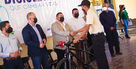 Montemorelos Mayor Miguel Salazar (shaking hands) and John Schroer (on his right) present a bicycle to a high school student from Montemorelos.