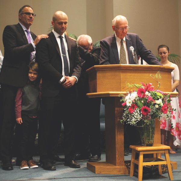 Pastors lay hands on Ostrovsky as he is ordained.