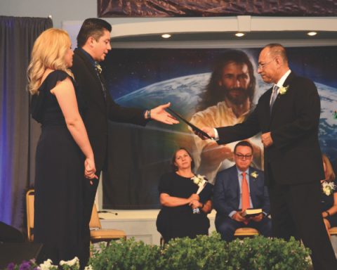 Elder Jorge A. Ramírez (right) gives Pastor Adino Salazar Cienfuegos and his wife, Dianni, the official ordination certificate. 