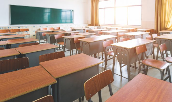 Empty classroom with desks, chairs and chalkboard.