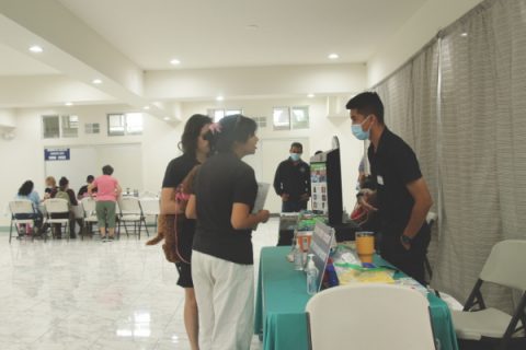 Two women speak to a representative at the COVID-19 vaccination and booster station.