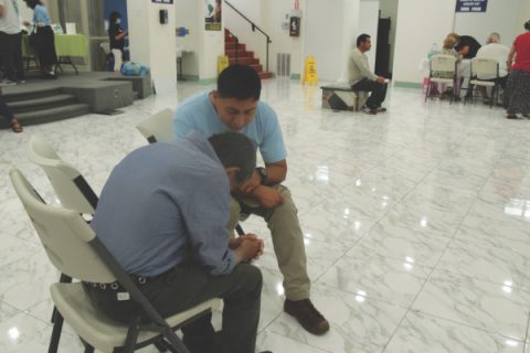 A volunteer from West Hollywood Spanish church prays with an attendee.