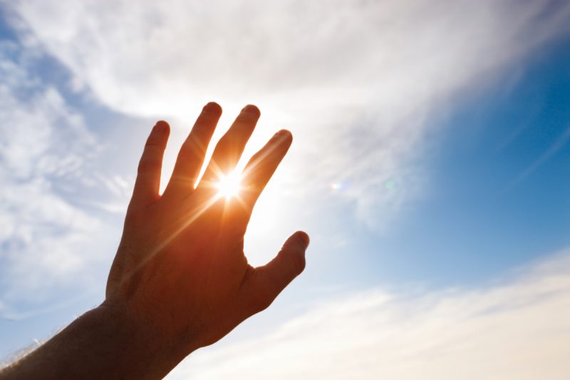 "Hand reaching for creations greatest source of renewable energy, the sun."