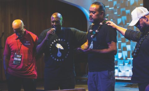 Fred Toailoa and James Black pray over Meshach Soli with Rome Ulia as they prepare for the anointing ceremony.