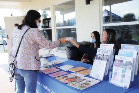 An attendee receives a Flowflex COVID-19 Antigen Home Test from the Los Angeles County Department of Public Health booth.