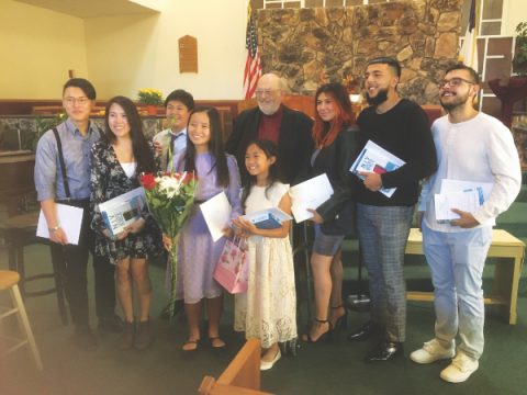 Newly baptized members of Sylmar church gather for a photo with Aitken (center), holding their new Bibles and certificates. (Left to right, front row) Mitchell Won, Tiffanie Pham, Joash Adlawan, Zyana Juan, Kysha Lastima, (left to right, back row) Destiny Fuentes, Adrienne Loaiza, and Michael Duarte. 